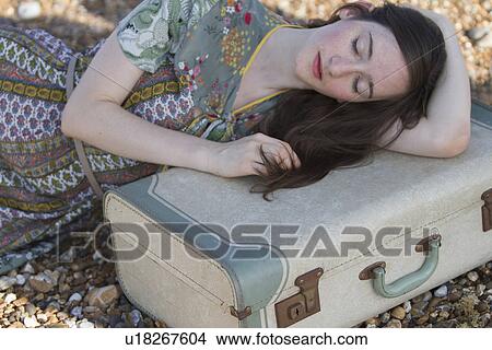 Portrait of young woman lying with suitcase on beach, Whitstable, Kent, UK View Large Photo Image Picture - Portrait of young woman lying with suitcase on beach, Whitstable, Kent, UK. Fotosearch