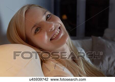 Portrait of young woman sitting on sofa View Large Photo Image Stock Image - Portrait of young woman sitting on sofa. Fotosearch