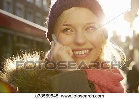 Stock Photography - Portrait of young woman wearing knit hat, telephone call. Fotosearch