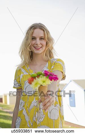Stock Image - Portrait of young woman with flower cone, Whitstable, Kent, UK. Fotosearch
