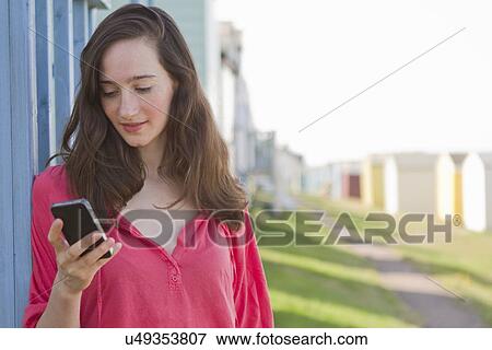 Stock Photo - Portrait of young woman with mobile phone, Whitstable, Kent, UK. Fotosearch