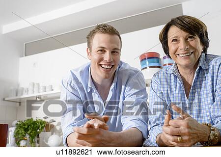 Stock Image - Portrait of youthful grandmother with grandson in kitchen. Fotosearch
