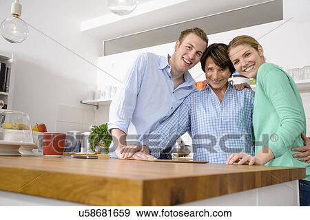 Stock Photo - Portrait of youthful grandmother with adult grandchildren in kitchen. Fotosearch
