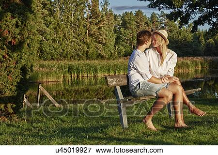 Stock Photo - Romantic young couple on park bench, Gavle, Sweden. Fotosearch