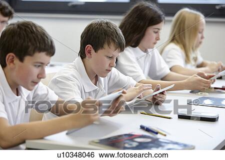 Row of schoolchildren working in class View Large Photo Image Stock Photograph - Row of schoolchildren working in class. Fotosearch