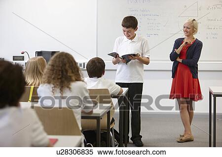 Schoolboy reading from textbook in front of class View Large Photo Image Stock Photography - Schoolboy reading from textbook in front of class. Fotosearch