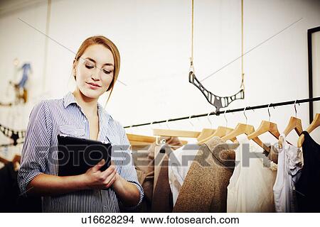 Shop keeper doing stock check using digital tablet View Large Photo Image Picture - Shop keeper doing stock check using digital tablet. Fotosearch