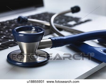 Stock Image - Stethoscope sitting on laptop illustrating online healthcare and doctor's desk. Fotosearch