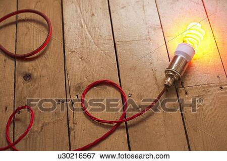 Stock Photo - Still life of energy saving lightbulb on wooden floorboards. Fotosearch