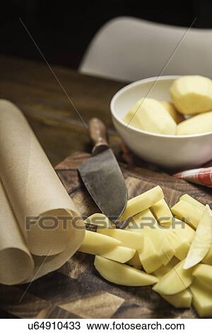 Stock Image - Still life of peeled and sliced potatoes and kitchen knife. Fotosearch