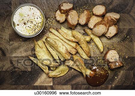Stock Photograph - Still life of potato fries, ketchup and currywurst. Fotosearch