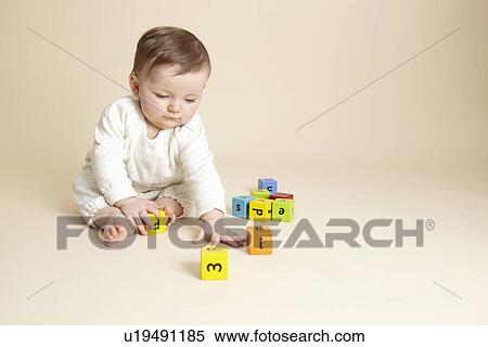 Stock Photography - Studio portrait of baby girl playing with alphabet blocks. Fotosearch
