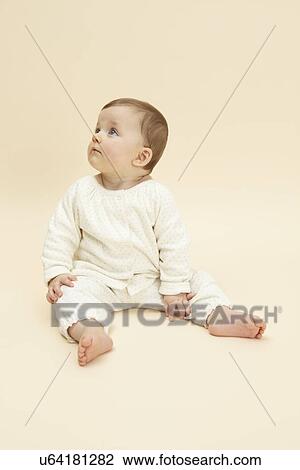 Stock Image - Studio portrait of distracted baby girl. Fotosearch