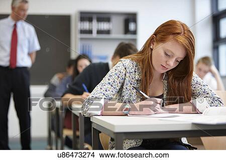 Picture - Teacher watching over teenagers in classroom. Fotosearch