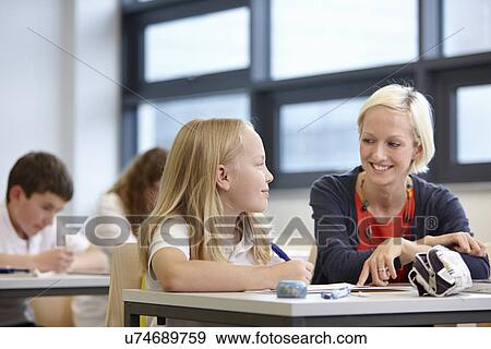 Stock Photo - Teacher working with schoolgirl in classroom. Fotosearch