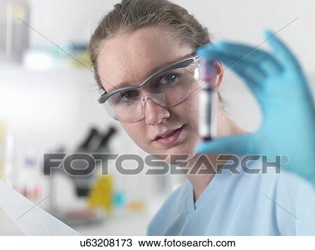Stock Image - Technician holding bar coded blood sample in clinical laboratory. Fotosearch