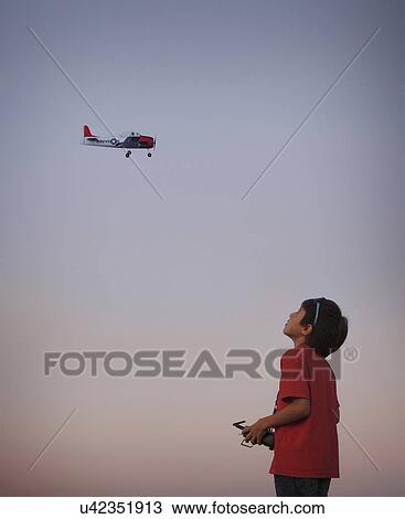 Stock Image - Teenage boy flying remote controlled aeroplane. Fotosearch