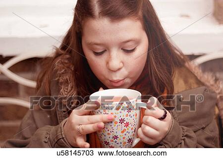 Teenage girl blowing on mug of coffee outdoors View Large Photo Image Stock Image - Teenage girl blowing on mug of coffee outdoors. Fotosearch