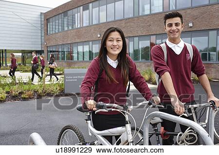 Stock Photo - Teenager friends with cycles outside school. Fotosearch