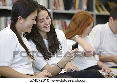 Stock Image - Teenagers hanging out in library. Fotosearch