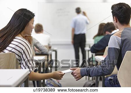 Teenagers passing secret note in class View Large Photo Image Stock Photo - Teenagers passing secret note in class. Fotosearch