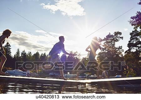 Stock Image - Three adult friends running along pier, Gavle, Sweden. Fotosearch