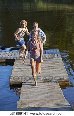 Stock Image - Three young adult friends running on pier, Gavle, Sweden. Fotosearch