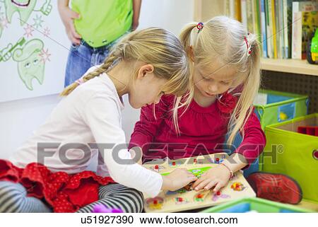 Stock Image - Two girls playing with puzzle at dentists. Fotosearch