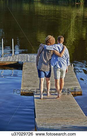 Stock Photograph - Two male adult friends strolling on pier, Gavle, Sweden. Fotosearch