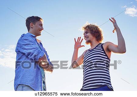 Two male friends enjoying conversation in sunlight View Large Photo Image Stock Photography - Two male friends enjoying conversation in sunlight. Fotosearch