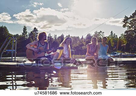 Stock Photograph - Two young couples relaxing on pier, Gavle, Sweden. Fotosearch