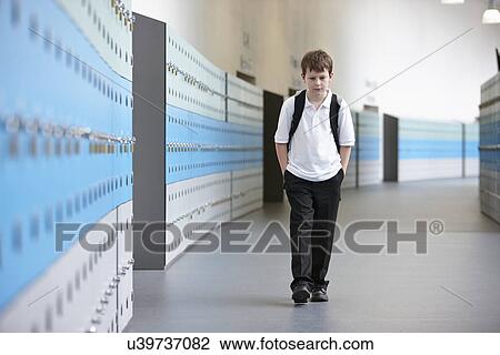 Stock Image - Unhappy schoolboy walking alone in school corridor. Fotosearch