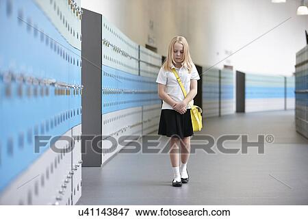 Stock Photo - Unhappy schoolgirl walking alone in school corridor. Fotosearch