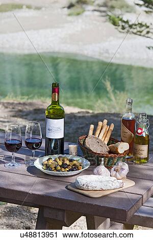 Stock Image - Wine and traditionally french food on picnic table. Fotosearch