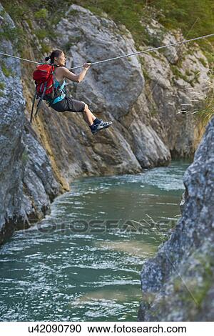 Stock Image - Woman crossing the Verdon gorge on a rope, Couloir du Samson, Canyon du Verdon, Provence, France. Fotosearch