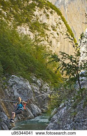 Stock Image - Woman crossing the Verdon gorge on a rope, Couloir du Samson, Canyon du Verdon, Provence, France. Fotosearch