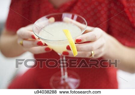 Stock Photo - Woman holding glass of cocktail. Fotosearch