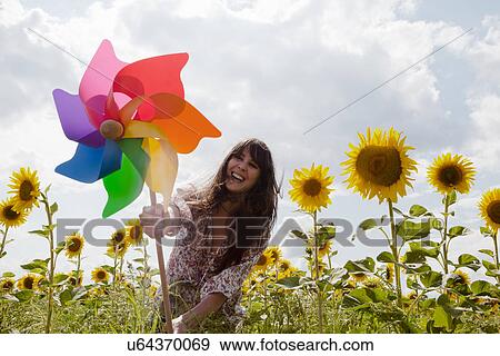 Woman holding windmill in field of sunflowers View Large Photo Image Stock Photo - Woman holding windmill in field of sunflowers. Fotosearch