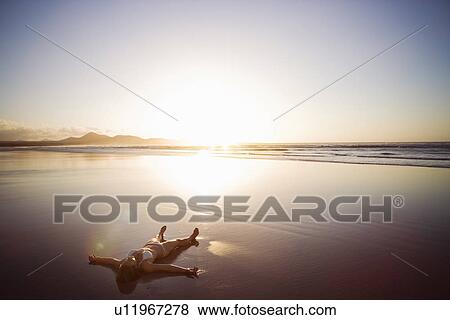 Woman lying on beach, Lanzarote, Canary Islands, Spain View Large Photo Image Stock Photo - Woman lying on beach, Lanzarote, Canary Islands, Spain. Fotosearch
