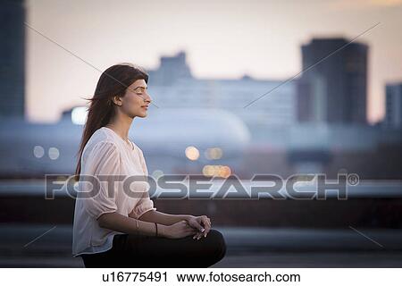 Woman meditating on rooftop View Large Photo Image Stock Image - Woman meditating on rooftop. Fotosearch