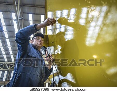 Worker on scaffolding in engineering factory, low angle view View Large Photo Image Stock Photo - Worker on scaffolding in engineering factory, low angle view. Fotosearch