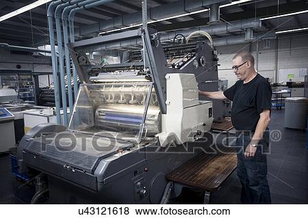 Worker operating print machine in printing workshop View Large Photo Image Stock Photo - Worker operating print machine in printing workshop. Fotosearch