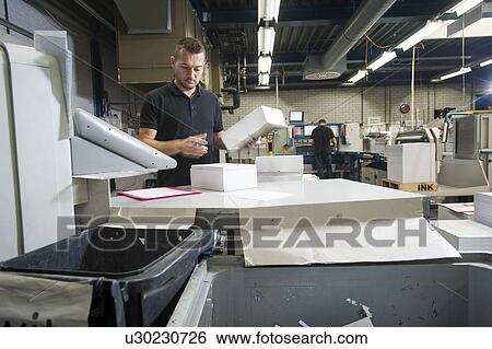Stock Photograph - Worker preparing paper for machine in print workshop. Fotosearch