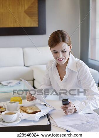 Picture - Young businesswoman using mobile phone in hotel room. Fotosearch