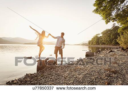Stock Photo - Young couple by lake, Cumbria, England, UK. Fotosearch