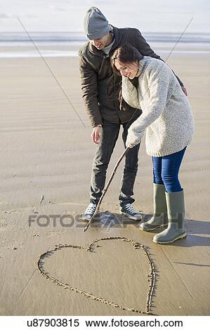 Young couple drawing heart in sand, Brean Sands, Somerset, England View Large Photo Image Stock Photography - Young couple drawing heart in sand, Brean Sands, Somerset, England. Fotosearch