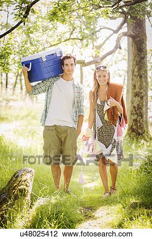 Stock Image - Young couple in forest with bunting and cool box. Fotosearch