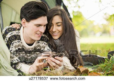 Young couple in tent using smartphone View Large Photo Image Stock Photo - Young couple in tent using smartphone. Fotosearch