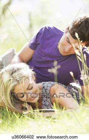 Stock Image - Young couple lying on grass. Fotosearch