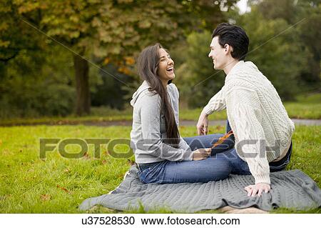 Young couple on blanket in park, laughing View Large Photo Image Stock Image - Young couple on blanket in park, laughing. Fotosearch